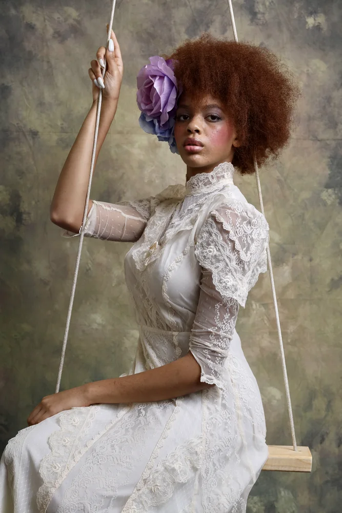Close editorial portrait on the swing — lace sleeves and purple flower crown
