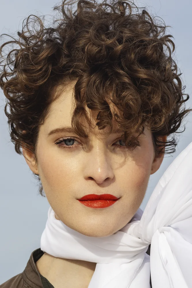 Beauty close-up on the dunes — red lips and wind-blown white scarf