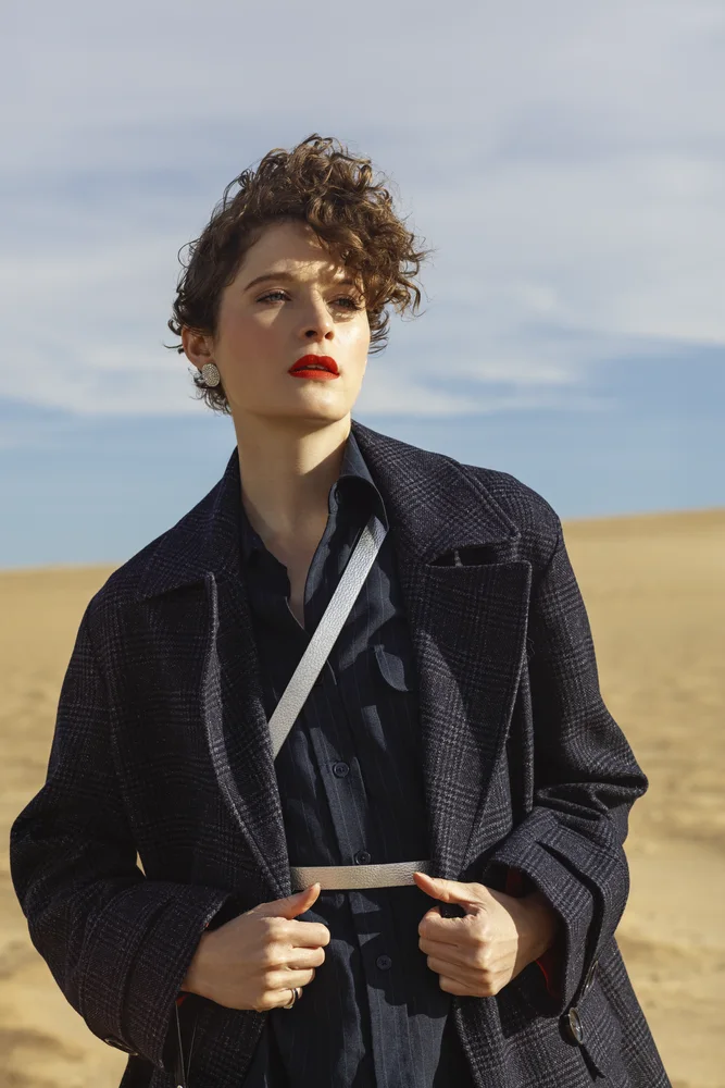 Fashion editorial on sand dunes — structured navy coat