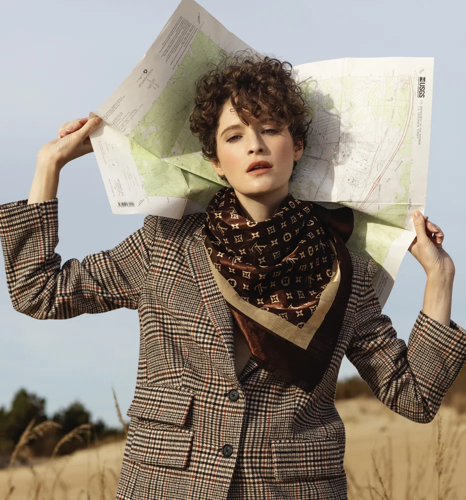 Autumn editorial — model holding an open map overhead in golden grass